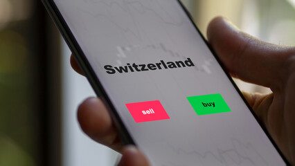 Un investisseur analyse le fonds ETF suisse à l'écran. Un téléphone montre les prix de l'ETF Suisse pour investir, texte en anglais.