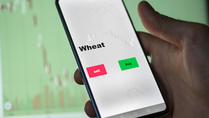 Un investisseur analyse le fonds ETF blé à l'écran. Un téléphone montre les prix de l'ETF des matières premières alimentaires à investir, texte en anglais.