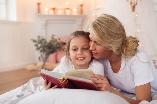 a mother and daughter reading a book on a bed, stock image, in the bedroom at a sleepover, full length shot, istock, photo of a beautiful, reading new book