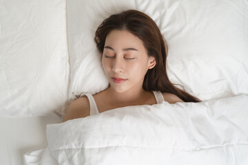 Top view of beautiful woman sleeping well on white soft pillow on the bed at home.