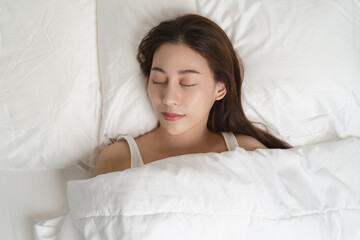 Obraz na płótnie Canvas Top view of beautiful woman sleeping well on white soft pillow on the bed at home.