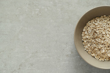 Dry oatmeal in a bowl isolated against a gray background.