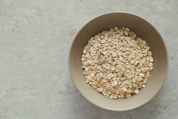 Raw oatmeal in a bowl isolated against a gray background.