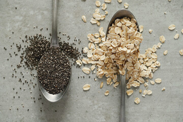 Spoonful's of raw oatmeal flakes and chia seeds on the table