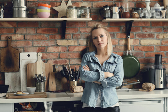 Image of a beautiful woman standing with crossed arms and looking at camera in the kitchen at home 