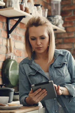 Image of an attractive woman holding digital tablet in the kitchen at home