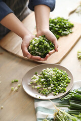 Women’s well-groomed hands make salad from greens in the kitchen