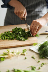 Women’s hands cut greens for salad in the kitchen 