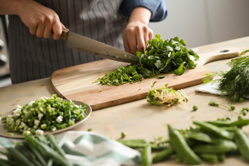 Women’s hands cut greens for salad in the kitchen 