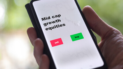 An investor's analyzing the mid cap growth equities etf fund on screen. A phone shows the ETF's prices midCap equity to invest
