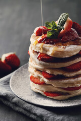 Beautifully decorated delicious sweet pancakes with fruits and honey on the plate