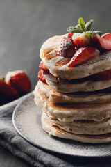 Beautifully decorated delicious sweet pancakes with fruits and honey on the plate