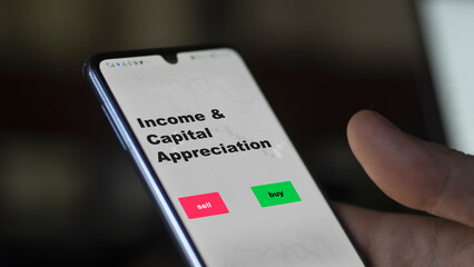 An investor's analyzing the income & capital appreciation etf fund on screen. A phone shows the ETF's prices stocks to invest