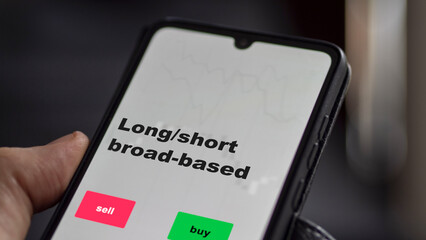 An investor's analyzing the long short broad-based etf fund on screen. A phone shows the ETF's prices long short broad based to invest