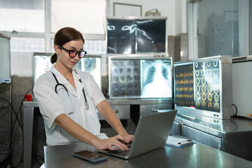 Woman radiology doctor working with laptop computer and checking x-ray film of patient in health care medical laboratory at hospital