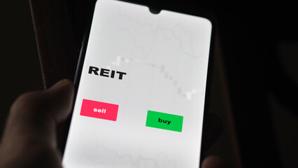 An investor's analyzing the REIT etf fund on screen. A phone shows the REITs ETF's prices real...