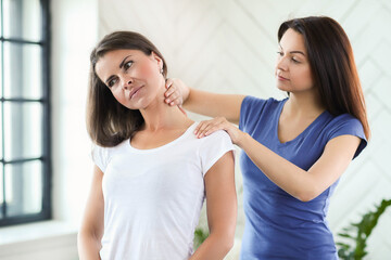 Professional massages the neck of a young woman at home