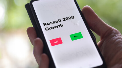 An investor's analyzing the Russell 2000 Growth etf fund on screen. A phone shows the ETF's prices russell to invest