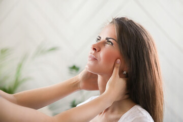 Professional massages the neck of a young woman at home