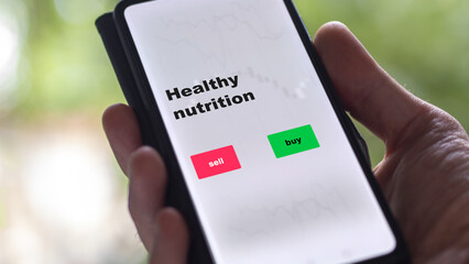 An investor's analyzing the healthy nutrition etf fund on screen. A phone shows the ETF's prices stocks to invest