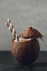 Fresh tasty juicy coconut drink with straw on dark background