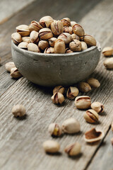 Image of pistachio nuts in bowl isolated on a wooden background.