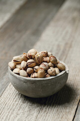 Image of pistachio nuts in bowl isolated on a wooden background.