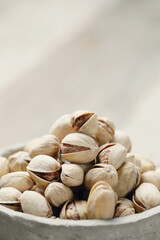 Close view of pistachio nuts in bowl isolated on a wooden background.