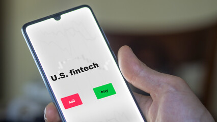 An investor's analyzing the stocks etf fund on screen. A phone shows the ETF's prices U.S. fintech to invest