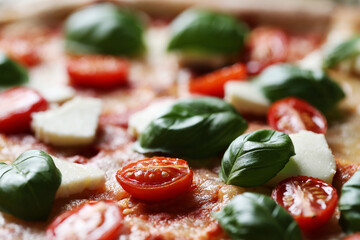 Close view of whole tasty pizza with cheese, cherry tomatoes and greens 