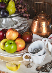 Autumn fruits, plates, cutlery and kitchen utencils on wooden table. Grapes, apples and pears on table.