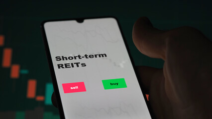 An investor's analyzing the reit on screen. A phone shows the ETF's prices short-term REITs