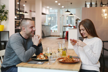 A young woman takes a picture of a meal at a romantic dinner with her husband at a restaurant