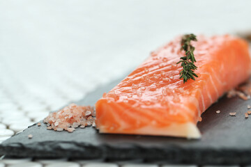 Fresh juicy raw salmon with rosemary and sea salt on a black cutting board