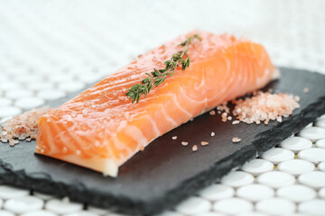 Fresh juicy raw salmon with rosemary and sea salt on a black cutting board