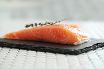 Picture of fresh juicy raw salmon with rosemary on a black cutting board