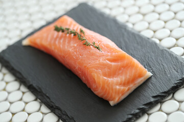 Top view of fresh juicy raw salmon with rosemary on a black cutting board