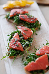 Close view of delicious Bruschetta (sandwiches) with slices of grapefruit,arugula and pumpkin seeds on a wooden cutting board 