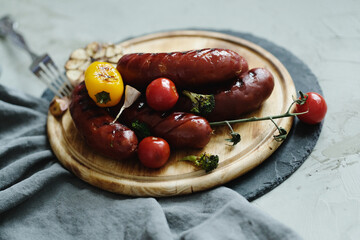 Tasty hot grilled food with sausage and various vegeables on a wooden plate
