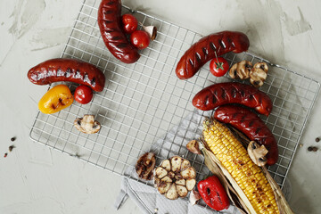 Top view of delicious hot grilled food with sausage,corn and other vegeables on a mesh grid