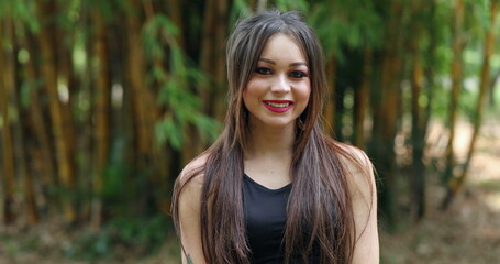 Portrait of young millennial woman in her 20s smiling to camera outdoors