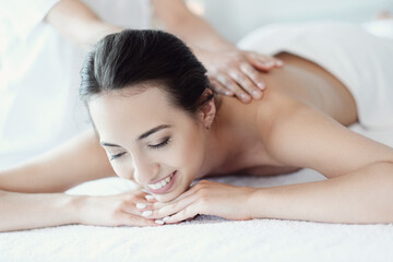 Fototapeta na wymiar Women’s hands giving a relaxing massage to a beautiful young woman in the spa salon