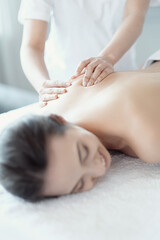 Fototapeta na wymiar A beautiful young woman enjoying a back massage in the spa salon