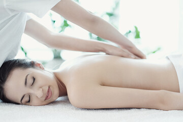 Obraz na płótnie Canvas A beautiful young woman enjoying a back massage in the spa salon