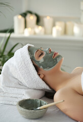A beautiful young girl lying in a spa salon with a clay mask on her face