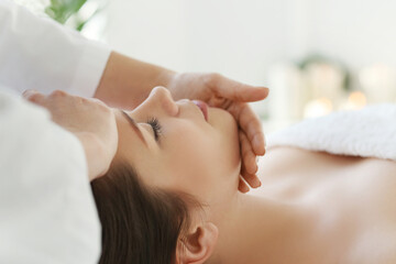 Fototapeta na wymiar Beautician doing face massage of young beautiful relaxed woman in spa salon