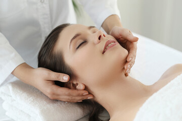 Fototapeta na wymiar Beautician doing massage of young beautiful relaxed woman in spa salon