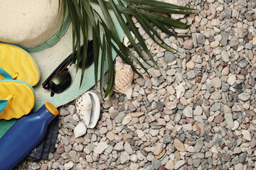 Beach hat, sunglasses, slippers and a bottle of water on the beach in shells
