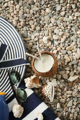 Delicious refreshing cold coconut drink with two straws on the beach with shells