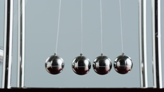 Newton balls close-up, five metallic pendulums on gray background, cradle. Physics and science concept.